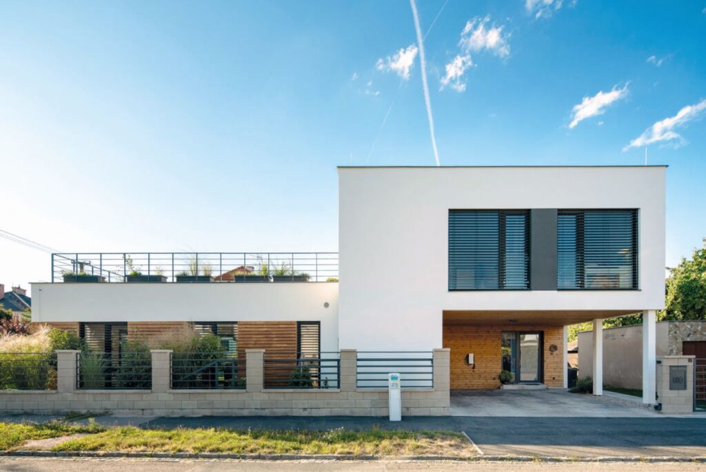 Elegantní geometrické tvary, podtržené kontrastem hladké bílé omítky, přírodního dřeva a antracitových okenních rámů, jsou základem nadčasové koncepce domu