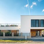Elegantní geometrické tvary, podtržené kontrastem hladké bílé omítky, přírodního dřeva a antracitových okenních rámů, jsou základem nadčasové koncepce domu